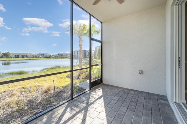 unfurnished sunroom featuring ceiling fan and a water view