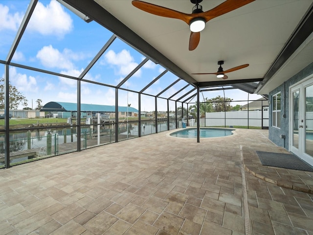 view of swimming pool with french doors, a water view, a patio area, and a lanai