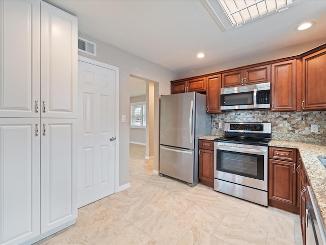 kitchen featuring light stone countertops, appliances with stainless steel finishes, and tasteful backsplash