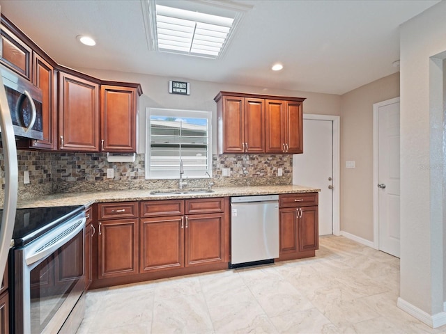 kitchen featuring light stone countertops, backsplash, stainless steel appliances, and sink