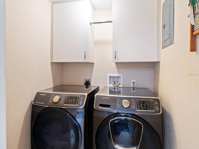 clothes washing area with washing machine and dryer, electric panel, and cabinets