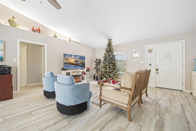 living room featuring ceiling fan, light hardwood / wood-style floors, and lofted ceiling