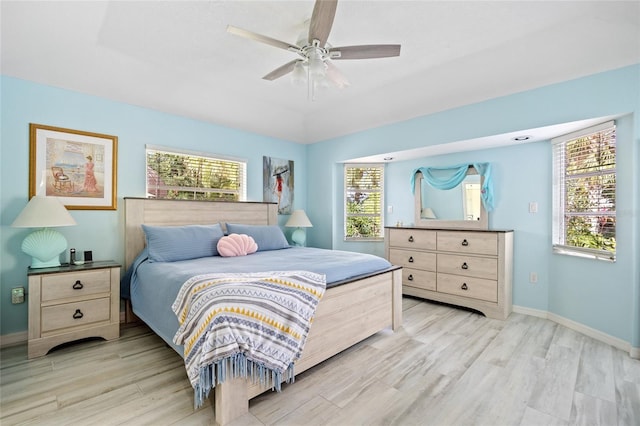 bedroom featuring ceiling fan, light wood-type flooring, and multiple windows