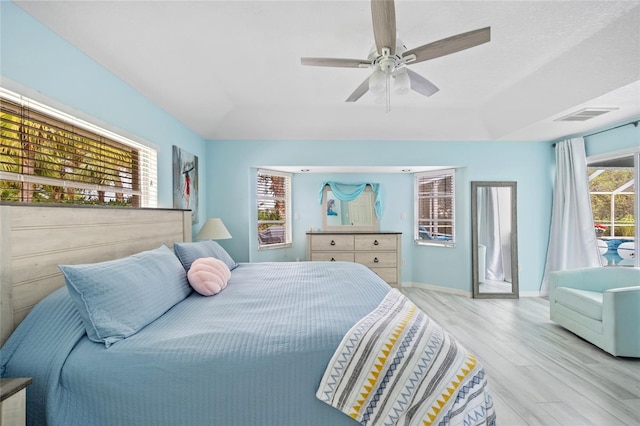 bedroom featuring light hardwood / wood-style flooring, multiple windows, and ceiling fan