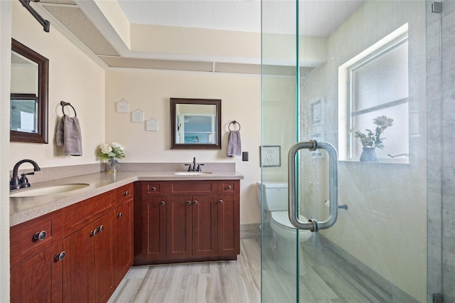 bathroom featuring hardwood / wood-style floors, vanity, toilet, and a shower with shower door