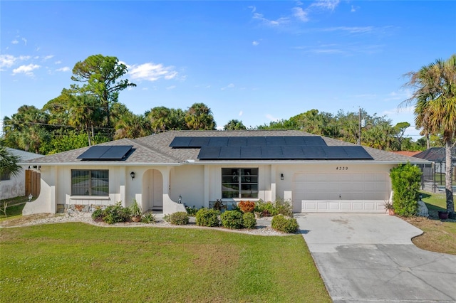 ranch-style home featuring a front yard, solar panels, and a garage