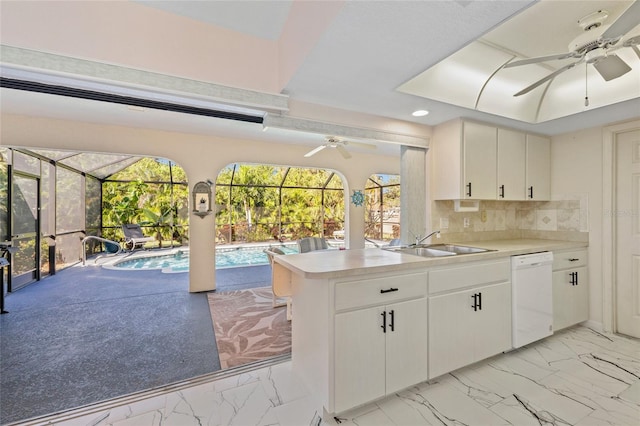 kitchen featuring dishwasher, backsplash, white cabinets, sink, and kitchen peninsula