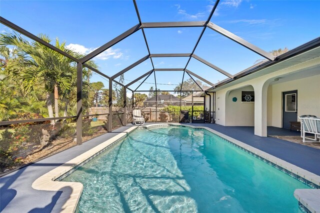 view of swimming pool with glass enclosure and a patio