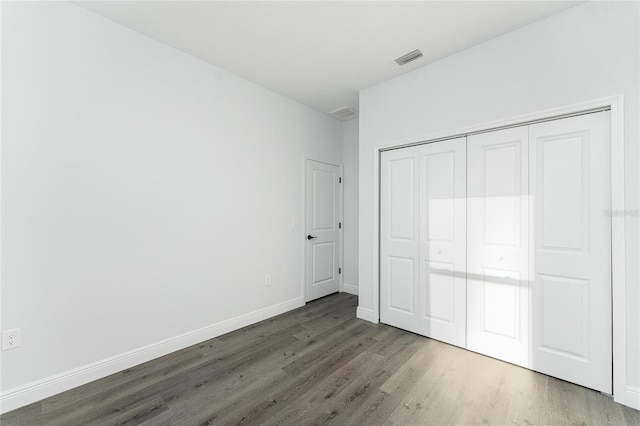 unfurnished bedroom with a closet and dark wood-type flooring