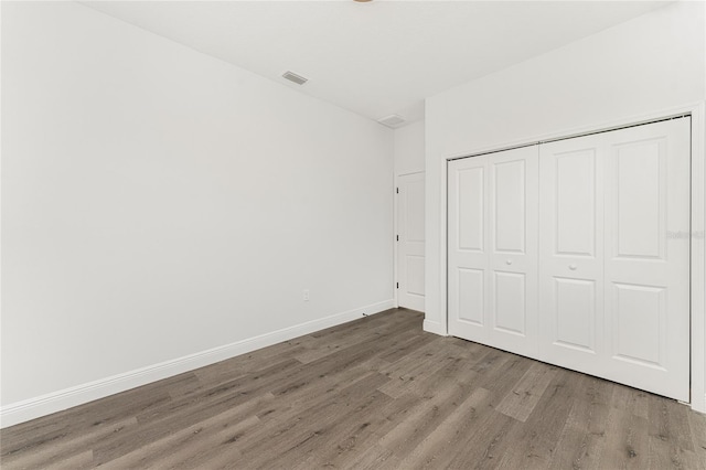 unfurnished bedroom featuring wood-type flooring and a closet