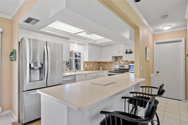 kitchen featuring a kitchen bar, stainless steel appliances, white cabinetry, and crown molding