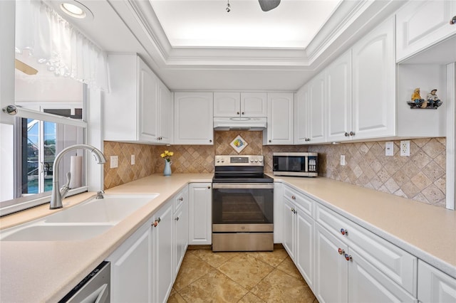 kitchen with appliances with stainless steel finishes, white cabinetry, a raised ceiling, and sink