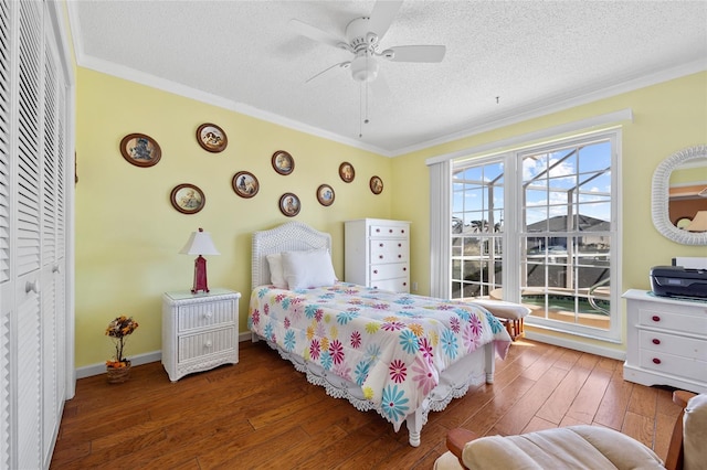 bedroom with a textured ceiling, ceiling fan, ornamental molding, and dark wood-type flooring