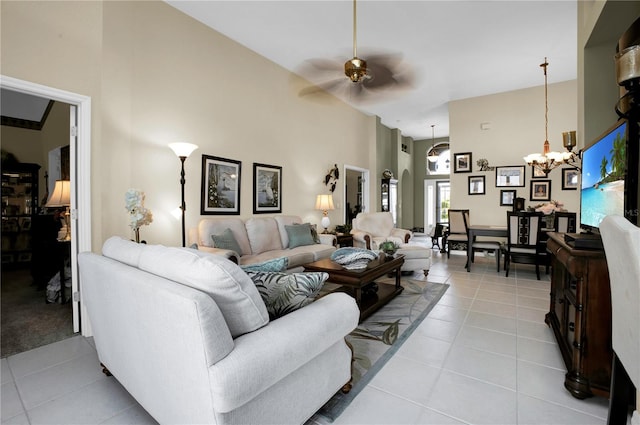 tiled living room featuring ceiling fan with notable chandelier and high vaulted ceiling