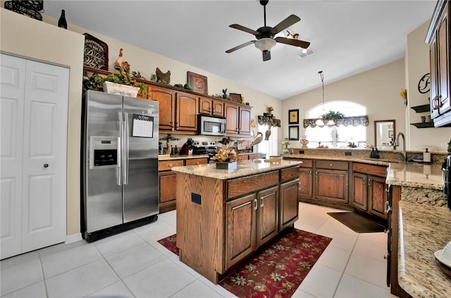 kitchen with light tile patterned flooring, appliances with stainless steel finishes, a kitchen island, and sink