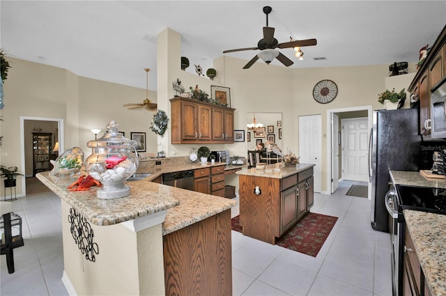 kitchen featuring light stone countertops, stainless steel appliances, light tile patterned floors, kitchen peninsula, and a kitchen island