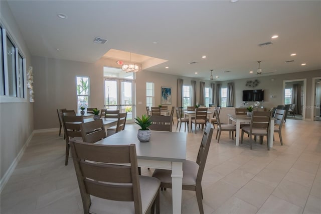 tiled dining room with ceiling fan with notable chandelier