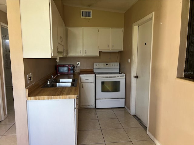 kitchen with white range with electric cooktop, sink, vaulted ceiling, light tile patterned floors, and cream cabinetry