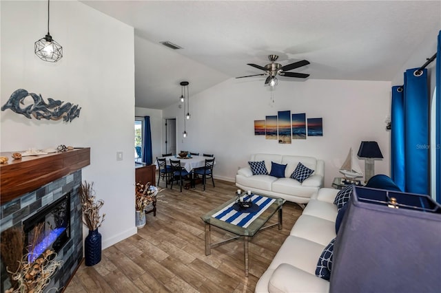 living room with ceiling fan, a fireplace, lofted ceiling, and hardwood / wood-style flooring