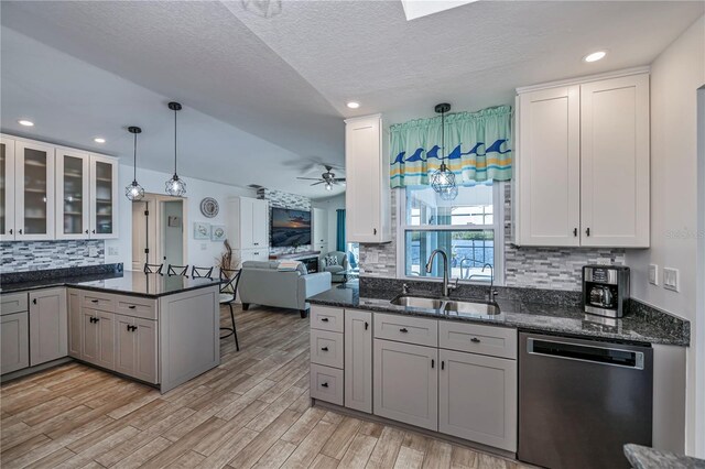 kitchen with kitchen peninsula, stainless steel dishwasher, ceiling fan, light hardwood / wood-style floors, and hanging light fixtures