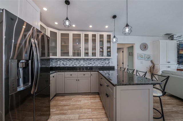 kitchen with a kitchen breakfast bar, tasteful backsplash, light hardwood / wood-style flooring, stainless steel fridge, and pendant lighting