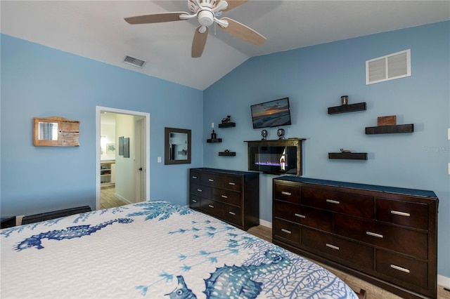 bedroom featuring light hardwood / wood-style flooring, ensuite bath, ceiling fan, and lofted ceiling