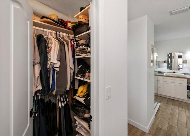 walk in closet with sink and light wood-type flooring