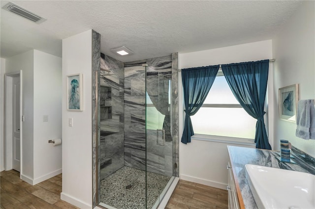 bathroom featuring hardwood / wood-style floors, vanity, walk in shower, and a textured ceiling