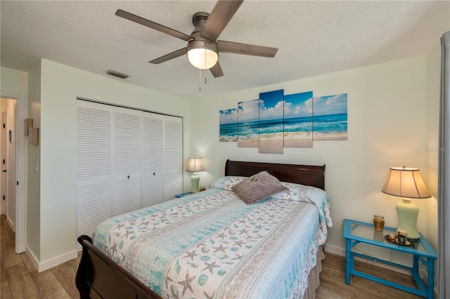 bedroom featuring ceiling fan, light hardwood / wood-style floors, a textured ceiling, and a closet