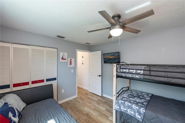 bedroom with a textured ceiling, light wood-type flooring, a closet, and ceiling fan