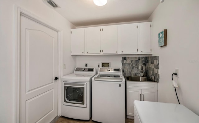 washroom with washing machine and dryer, sink, cabinets, and dark hardwood / wood-style flooring