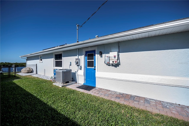 doorway to property with a lawn and central air condition unit