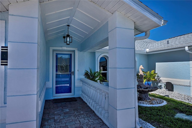 entrance to property with a shingled roof and stucco siding