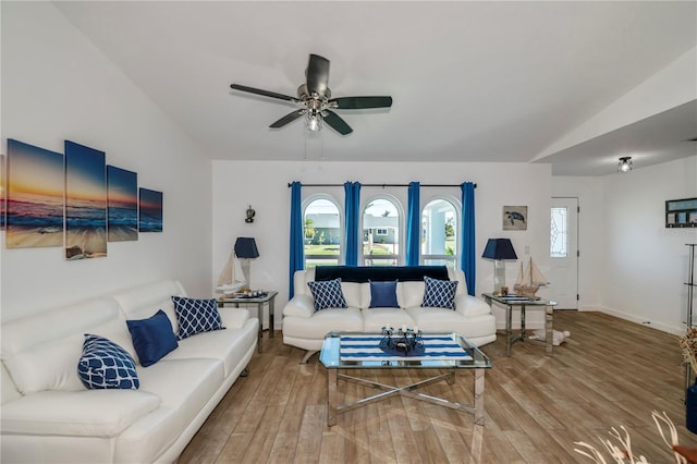 living area with ceiling fan, vaulted ceiling, baseboards, and wood finished floors