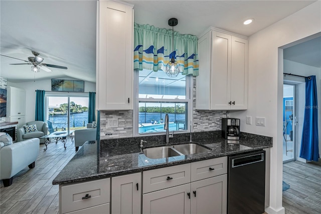 kitchen with black dishwasher, white cabinets, a sink, and open floor plan