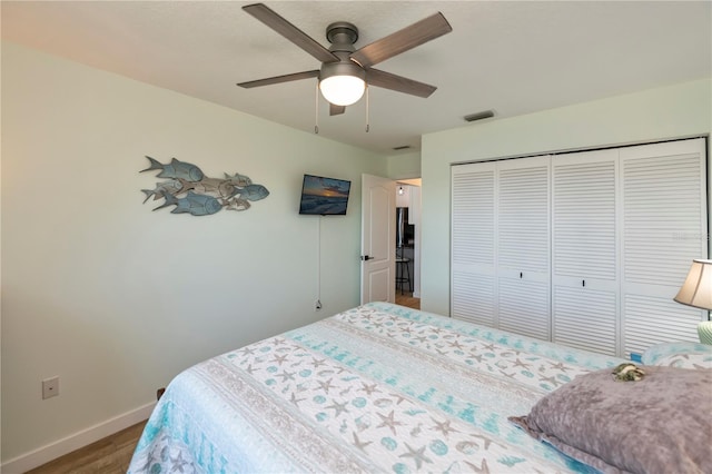 bedroom with a closet, visible vents, ceiling fan, wood finished floors, and baseboards