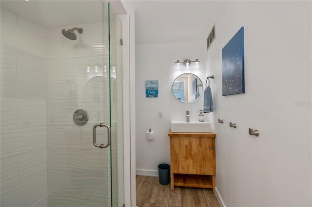 full bath with wood finished floors, vanity, visible vents, baseboards, and a stall shower