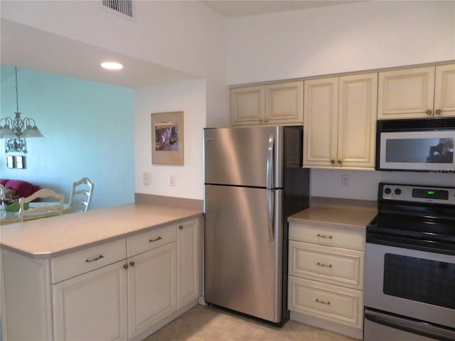 kitchen with kitchen peninsula, stainless steel appliances, pendant lighting, cream cabinets, and a notable chandelier