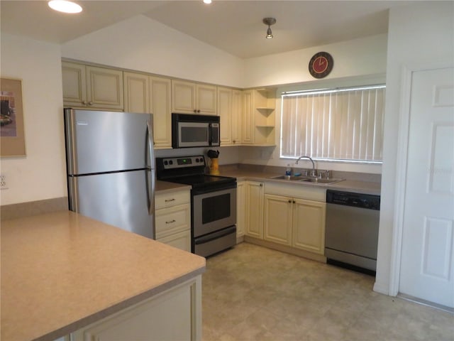 kitchen featuring cream cabinets, sink, stainless steel appliances, and lofted ceiling