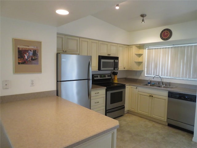 kitchen with cream cabinetry, sink, stainless steel appliances, and vaulted ceiling