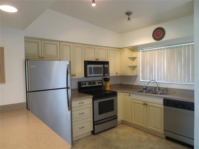 kitchen with cream cabinetry, sink, stainless steel appliances, and vaulted ceiling