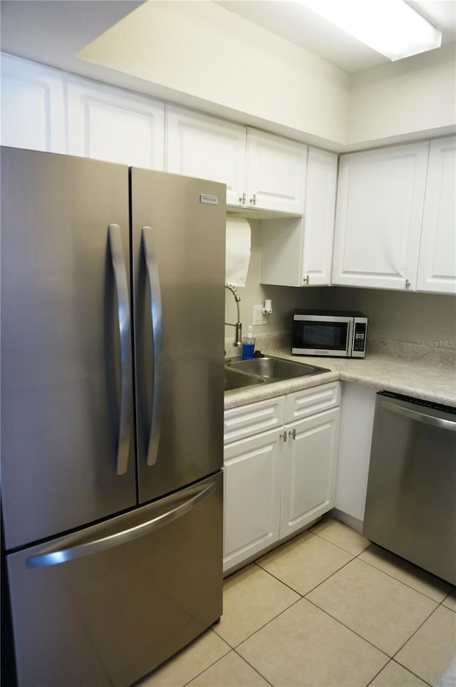 kitchen with light tile patterned flooring, white cabinetry, sink, and appliances with stainless steel finishes