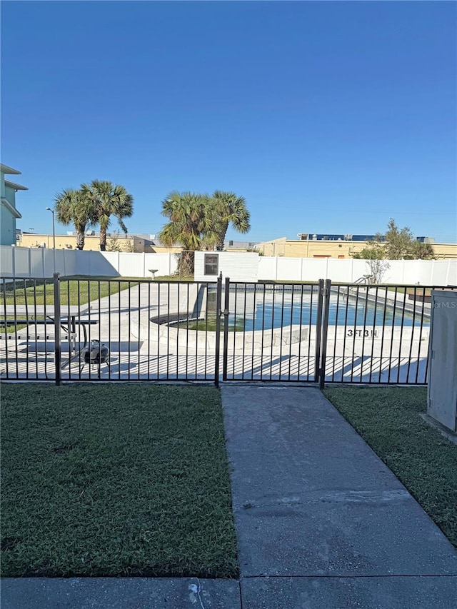 view of gate featuring a fenced in pool and a lawn