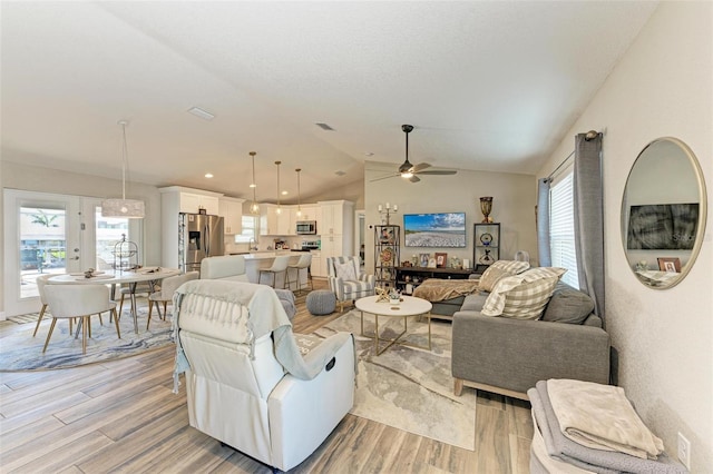 living room featuring lofted ceiling, light hardwood / wood-style floors, and a healthy amount of sunlight