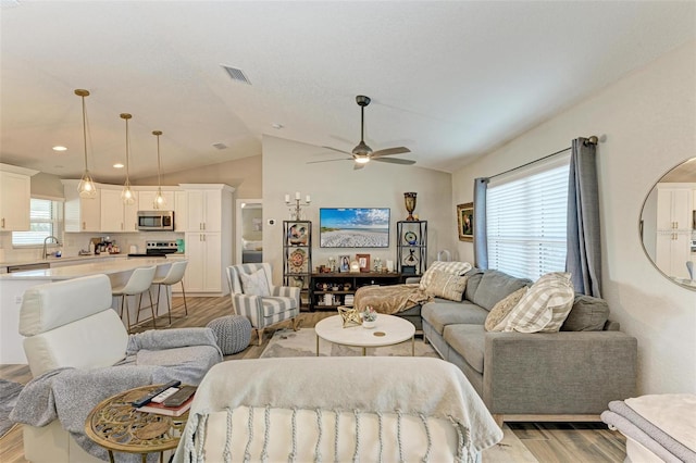 living room featuring light hardwood / wood-style floors, ceiling fan, lofted ceiling, and sink