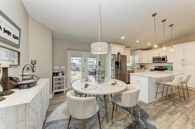 dining room featuring lofted ceiling, french doors, sink, and light hardwood / wood-style flooring