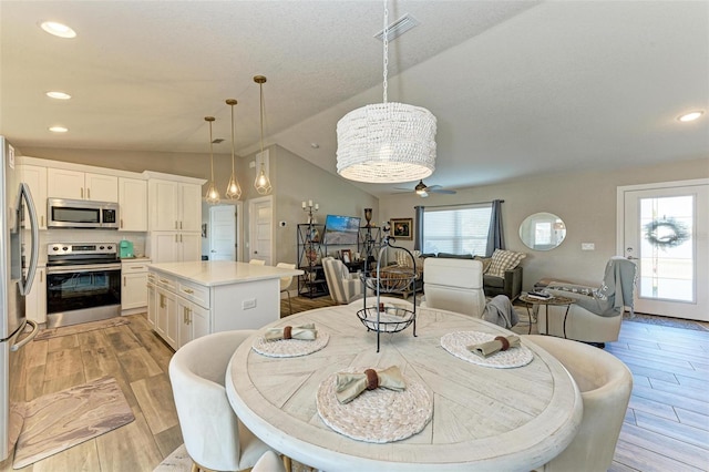 dining space with light hardwood / wood-style flooring, ceiling fan, and lofted ceiling