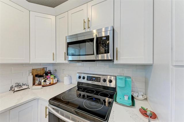 kitchen with decorative backsplash, light stone countertops, white cabinetry, and stainless steel appliances