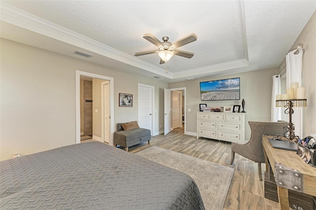 bedroom featuring a textured ceiling, a raised ceiling, ceiling fan, crown molding, and light hardwood / wood-style floors