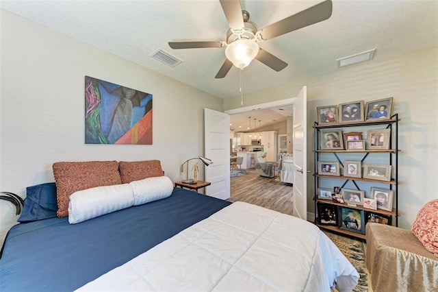 bedroom featuring hardwood / wood-style floors, ceiling fan, a textured ceiling, and vaulted ceiling